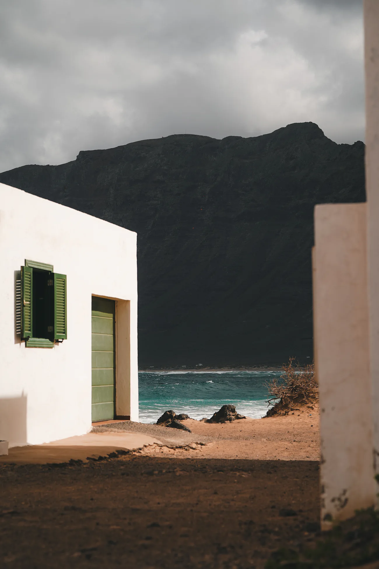 Casa blanca de arquitectura canaria con contraventanas verdes frente al mar